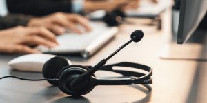 Panorama focus headset on call center workspace desk with blur background of operator team or telesales representative engage in providing client with customer support service or making sales. Prodigy
