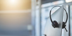 Call center, headset on a computer in an empty office with flare and mockup for communication or assistance. Customer care, support and equipment in a workplace after hours for help or service