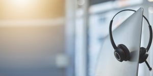 Call center, headset on a computer in an empty office with flare and mockup for communication or assistance. Customer care, support and equipment in a workplace after hours for help or service