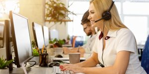 Friendly woman operator consulting client. Business team working at call center office, empty space