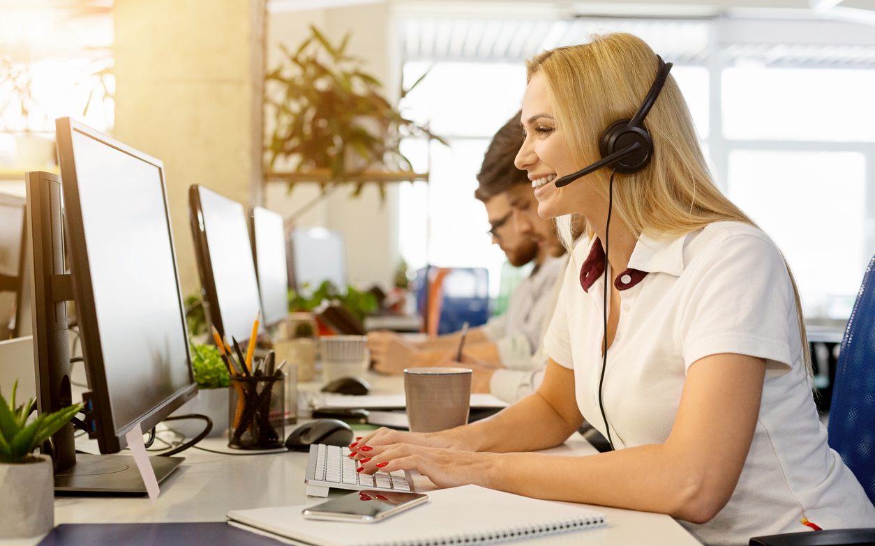 Friendly woman operator consulting client. Business team working at call center office, empty space