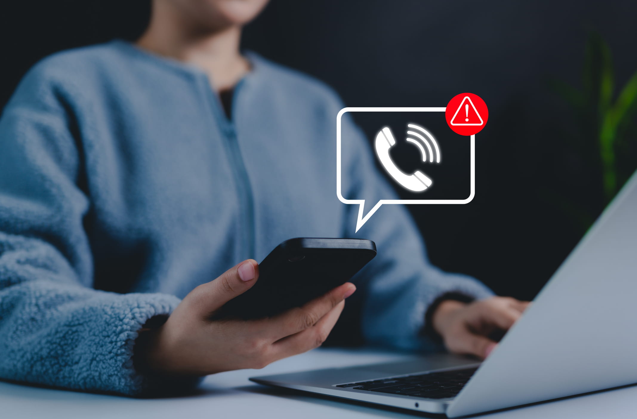 A person holding a smartphone with a digital scam warning notification