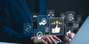 Businessman types on a laptop with icons representing service excellence