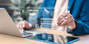 Business professional reviewing digital compliance documents on laptop and tablet